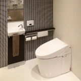 Eine moderne japanische Toilette, mit Bedientableau an der Wand neben dem Waschbecken. Sie bieten alle möglichen Funktionen, nur benutzen muss man sie noch selbst.